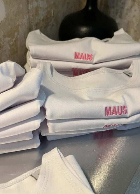 Detailaufnahme des pinken „MAUS“-Schriftzugs auf weißem Crop Top by Dejan Garz
