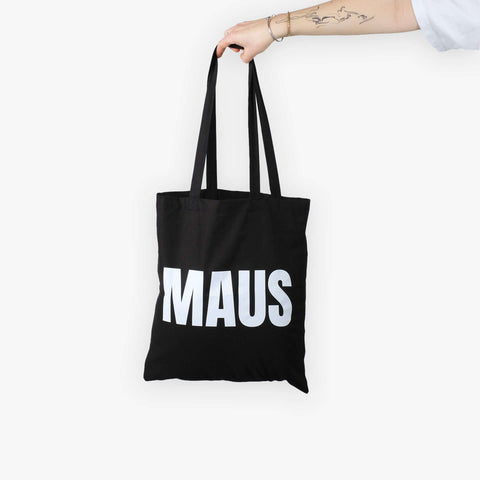 Detailaufnahme des weißen „MAUS“-Schriftzugs auf schwarzem Stoffbeutel by Dejan Garz